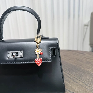 Detail of cute animal ladybug and daisy metal charms hanging on a black handbag