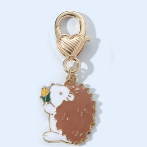 Detail of cute hedgehog enamel keychain with golden lobster clasp and heart texture