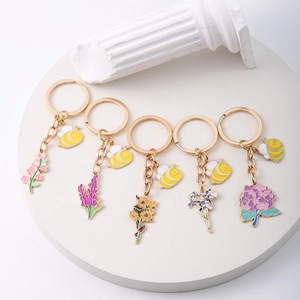 Detail view of five floral zinc alloy keychains with honey bee charms and colorful enamel