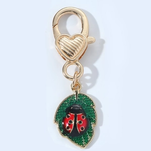 Detail of ladybug and leaf enamel pendant with golden heart-shaped lobster clasp