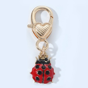 Detail of ladybug keychain with red enamel wings and black crystal spots on gold metal