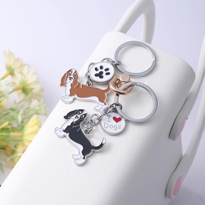 Détail de porte-clés chien Basset Hound avec breloques I Love Dogs sur un sac blanc
