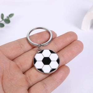 Classic black and white football soccer ball keychain pendant in hand against white background