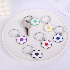 Zinc alloy soccer ball keychain set in six colors with metallic ring on a ceramic tray
