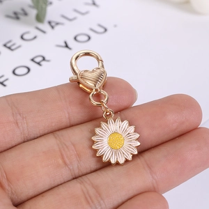 Detailed macro view of daisy keychain charm with golden heart lobster clasp