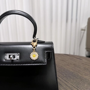 Detailed close-up of a zinc alloy daisy pendant with a gold heart clasp on a leather bag