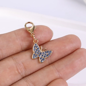 Detail view of a gold-tone butterfly pendant with blue rhinestones and lobster clasp