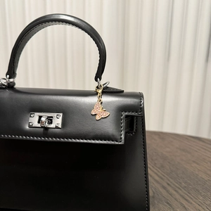 Detail of pink crystal butterfly charm on black leather handbag with silver clasp