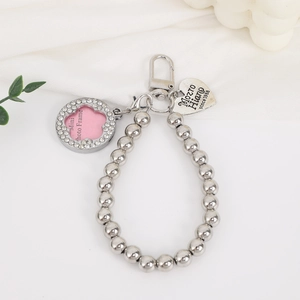 Macro detail of silver bead charm with heart tag and crystal photo frame pendant