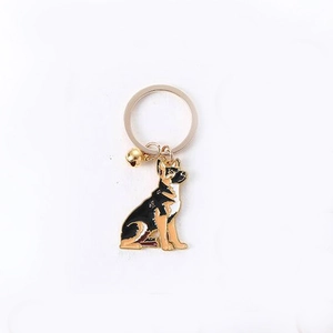 German Shepherd metal keychain with gold bell pendant and enamel finish on white background