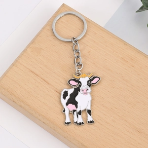 Détail d'un porte-clés vache mignon en émail posé sur un bloc en bois naturel