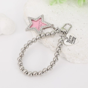Detailed view of silver beaded charm with rhinestone star and heart pendant on stone