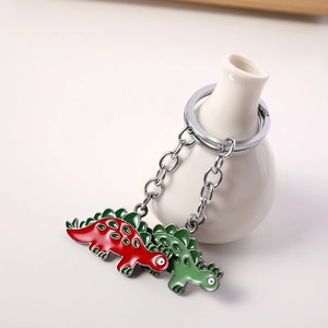 Cute red and green dinosaur keychain accessories on a white vase for bag decor