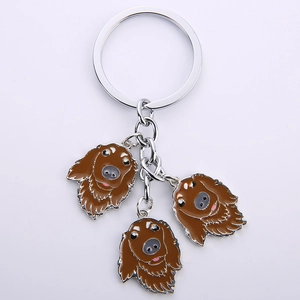 Detail view of silver metal keychain with three brown enamel cartoon dog head pendants