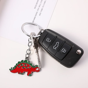 Detail view of a red cartoon dinosaur keychain with silver metal clasp on white background