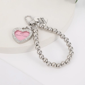 Macro shot of heart-shaped photo frame charm with rhinestones and beaded metal chain