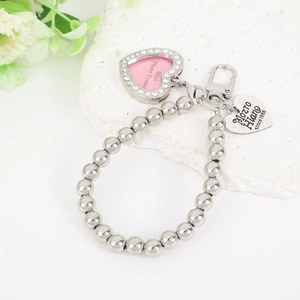 Close-up of a silver beaded keychain with a sparkling heart photo frame and engraved tag