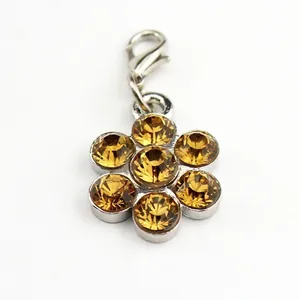 Flower shaped pet pendant with amber rhinestones and silver lobster clasp in a macro view