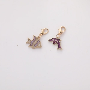 Dettaglio di ciondoli a forma di pesce tropicale e delfino viola con base dorata e ganci