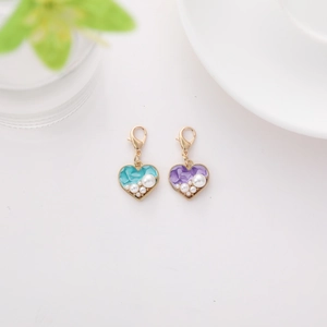 Dettaglio di ciondoli a forma di cuore con perle bianche e bordo dorato in blu e viola