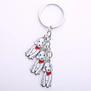 Detailed view of silver metal keychain with three white poodle pendants and red scarves