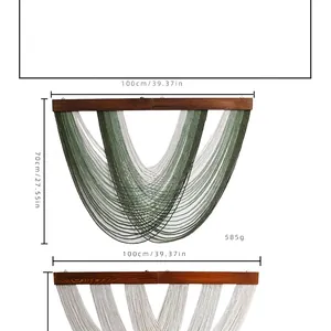 Detail of bohemian woven wall hanging with green and beige cotton fringe and wood bar