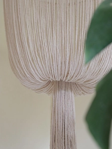Close-up of bohemian hand-woven cotton lamp shade with intricate macrame tassel details