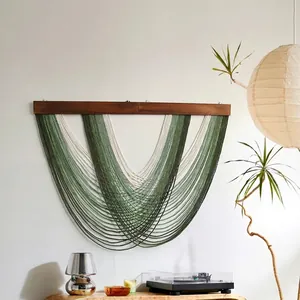 Close-up of bohemian hand-woven green cotton wall hanging tapestry with fringe