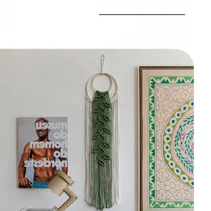 Detail of woven boho wall hanging with green leaf patterns and long white tassels