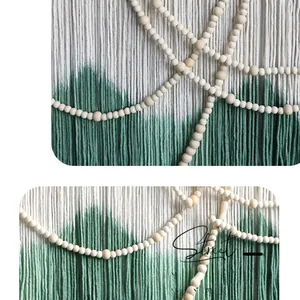 Detail of bohemian hand-woven tapestry with green gradient cotton cords and wooden beads