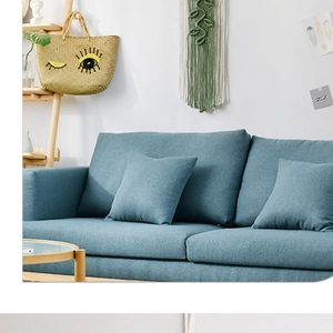 Detail of woven boho tapestry wall hanging behind a blue fabric three-seater sofa