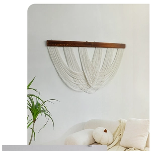 Detail of bohemian handmade woven wall tapestry with layered fringe on a wood rod
