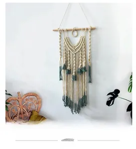 Detail of bohemian hand-woven tapestry featuring cream cotton rope and sage green tassels