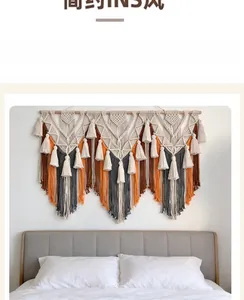 Détail d'une tapisserie Boho tissée main avec glands orange et marron sur tige en bois