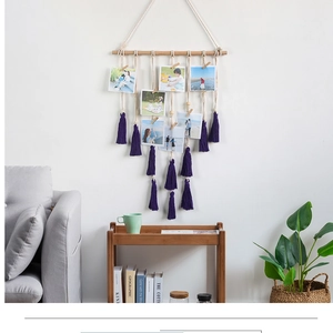 Detailed view of woven cotton rope photo display with wood stick and purple tassels