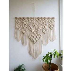 Detail view of handmade macramé wall hanging with bohemian fringe and wooden pole