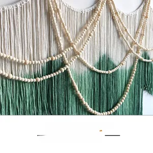Detailed close-up of bohemian woven tapestry with green dip-dye fringe and wooden beads