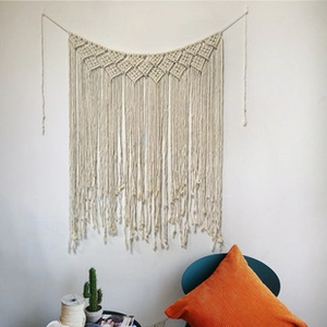 Detailed view of hand-woven cotton macrame tapestry with fringe and geometric knots