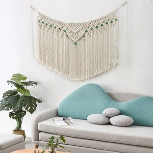 Detail of bohemian macrame wall hanging with ivory cotton ropes and green bead accents