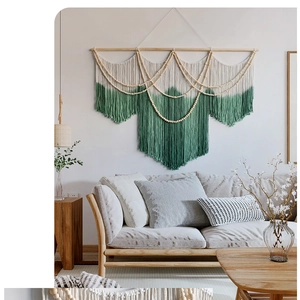 Detail of bohemian woven tapestry with forest green ombre fringe and wooden bead accents