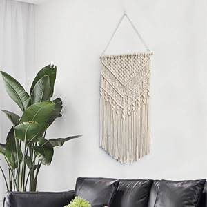 Handmade macrame wall hanging with cotton fringes and wooden pole for boho home decor
