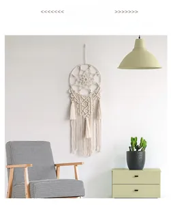 Detailed view of handmade bohemian wall hanging featuring woven cotton and white tassels