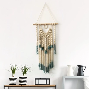 Handmade macrame wall hanging with off-white cotton rope and dark teal fringe on wood rod
