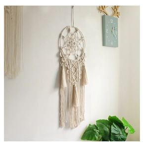 Detail of bohemian handmade woven wall hanging featuring cotton fringe and circular frame