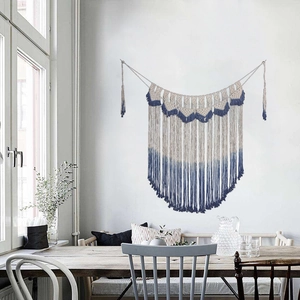 Detail of bohemian handmade woven wall hanging featuring blue and white gradient tassels