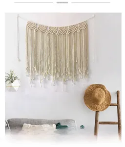 Detail of bohemian hand-woven macrame wall hanging with ivory cotton ropes and tassels