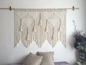 Detail of bohemian hand-woven tapestry featuring geometric patterns and wooden beads