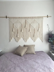 Detail of bohemian handmade cotton woven tapestry with tassel patterns on bedroom wall