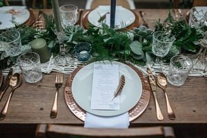 Detailed close-up of woven table runner with rose gold cutlery and forest green decor