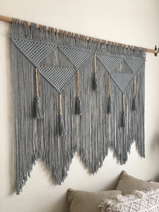 Close-up of Bohemian wall tapestry with grey cotton weaving and wood bead details